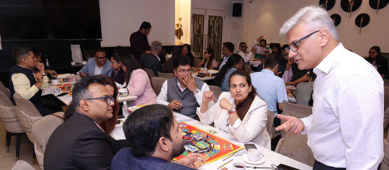 Business owners around the LEVERAGE board while Sanjay works the table